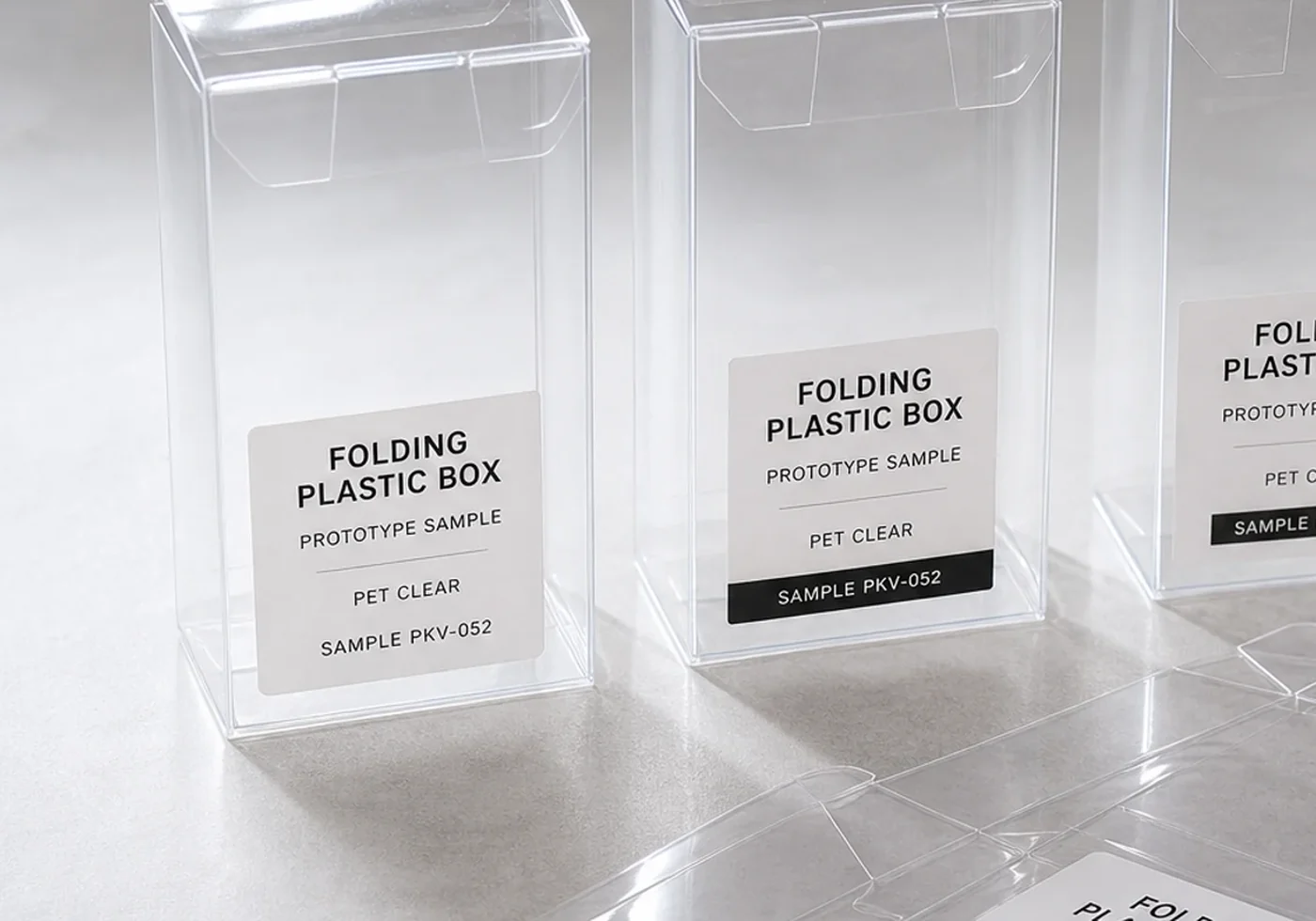 Folding plastic box close-up showing PET panels, scored fold lines, and clear closure tabs